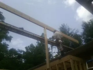 Carpenter setting a ridge beam over a new addition frame — Ice Dam Removal by Roofing Brothers in Newton Highlands