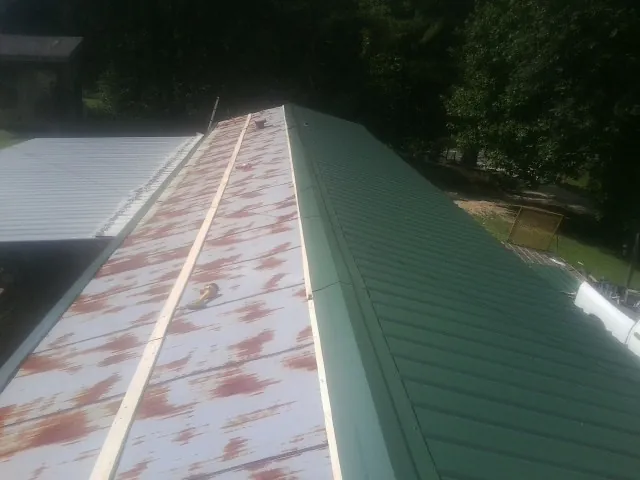 Old rusted panels beside newly installed green metal roofing — Wind Damage Roof Repair by Roofing Brothers in Newton Highlands