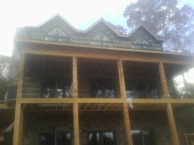 Dormers and porch framing on a large log home under construction — Roof Coating work by our crew in Newton Highlands