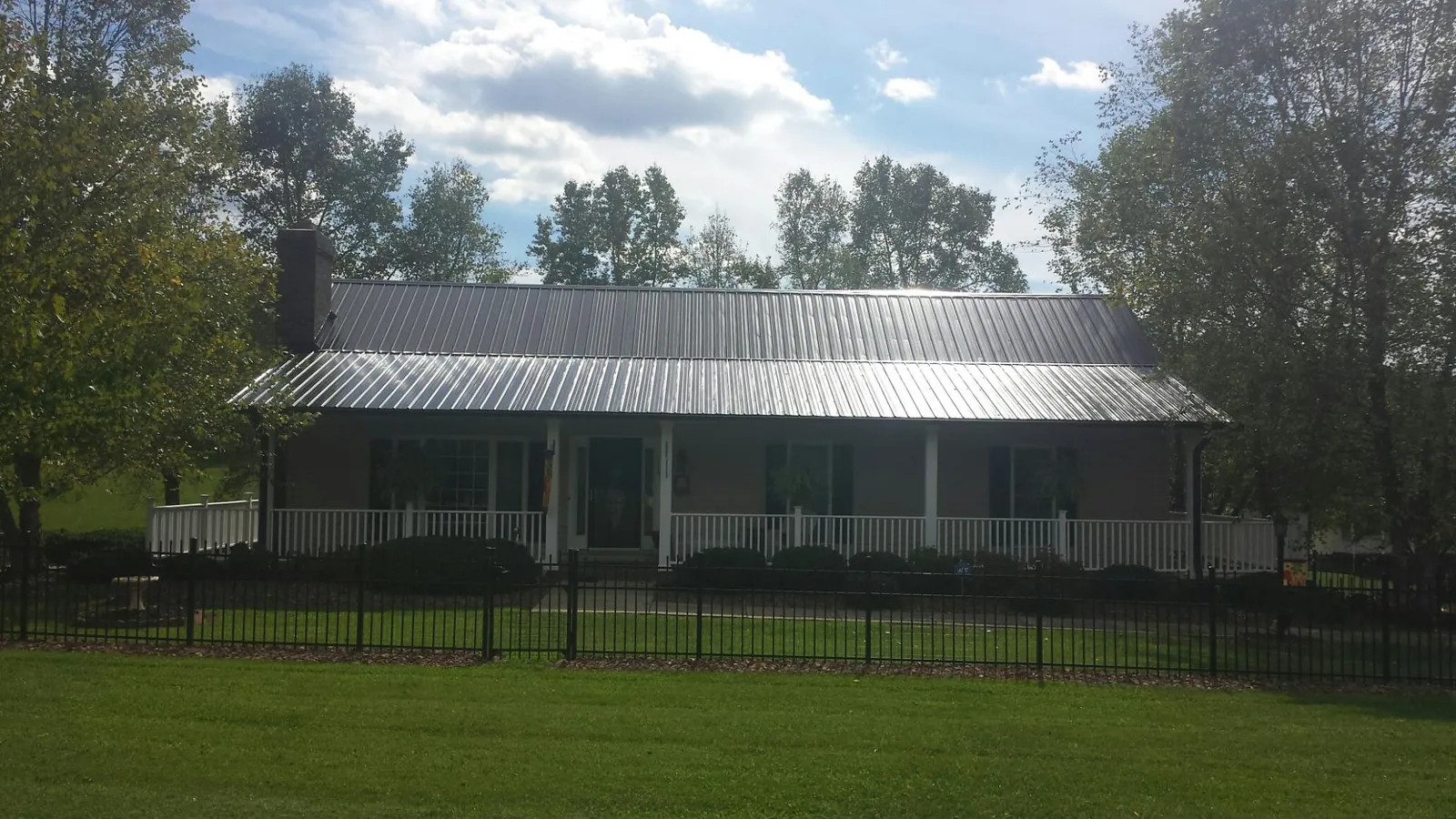 Gray metal roof on a brick ranch with a full width front porch — Gutter Guard Installation work by our crew in Newton Highlands