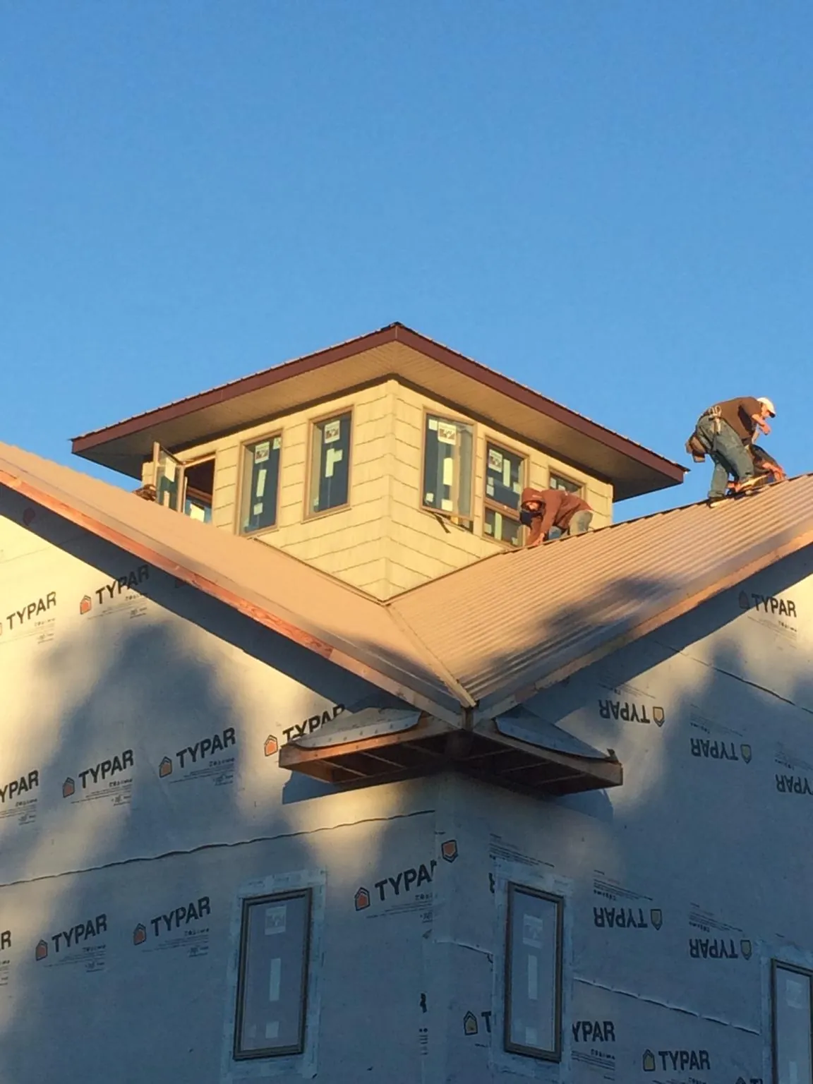 Roofers working around a rooftop cupola on a new metal roof at sunset — Roof Waterproofing in Newton Highlands by Roofing Brothers
